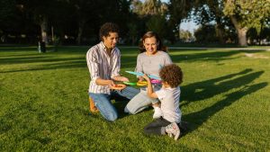 Family playing ring toss together enjoying sunny day in park.