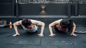 Two adults doing push-ups in an indoor gym setting in Mexico City, promoting a fit and healthy lifestyle.