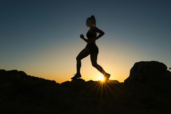 A woman runs up a trail during sunset.